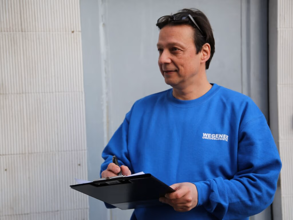 Der Inhaber der Firma Wegener Umzugslogistik hält ein Klemmbrett in der Hand und plant einen großen Umzug.
