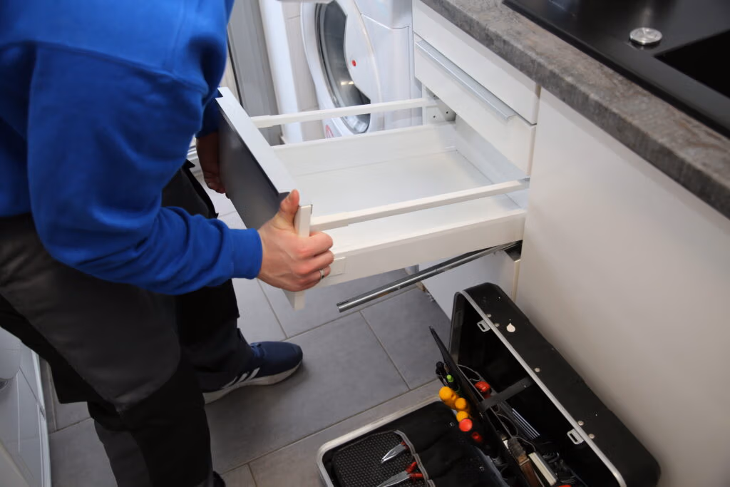 Küchenmonteur des Umzugsunternehmens Wegener Umzugslogistik baut eine Schublade in eine Küche ein.