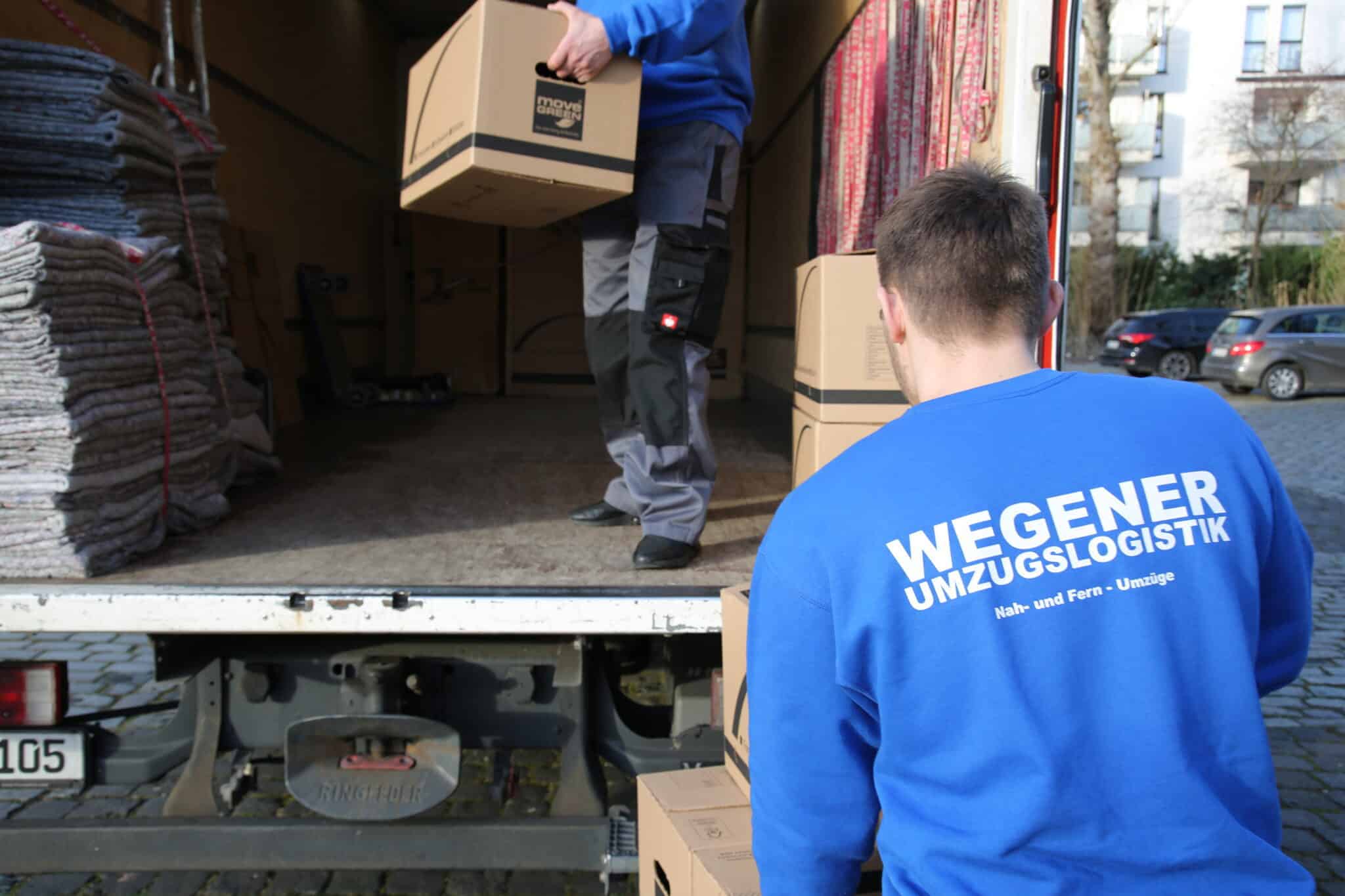 Zwei Umzugshelfer des Umzugsunternehmens Wegener Umzugslogistik in Köln beladen einen Umzugstransporter.