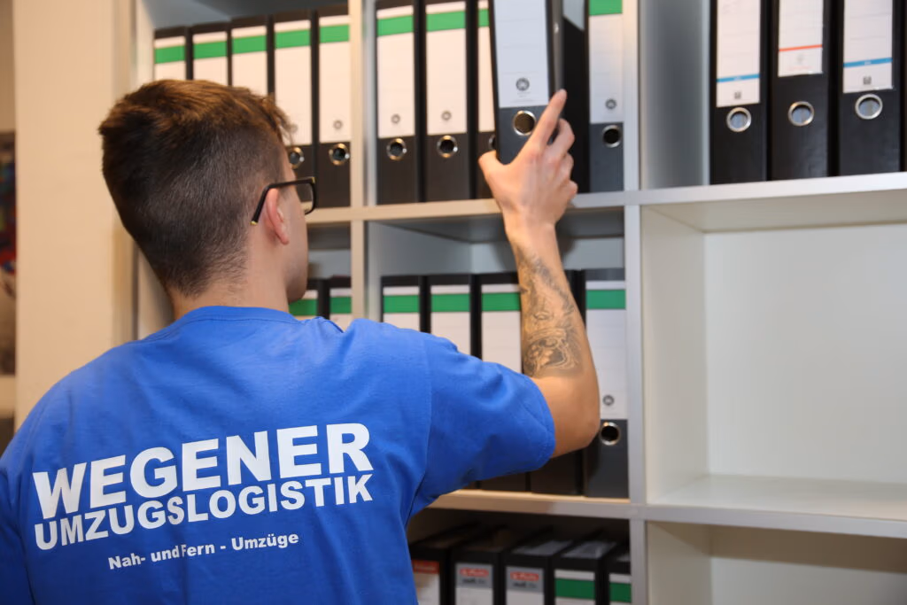 Ein Mitarbeiter des Umzugsunternehmens Wegener Umzugslogistik packt Ordner im Rahmen eines Büroumzuges ein.
